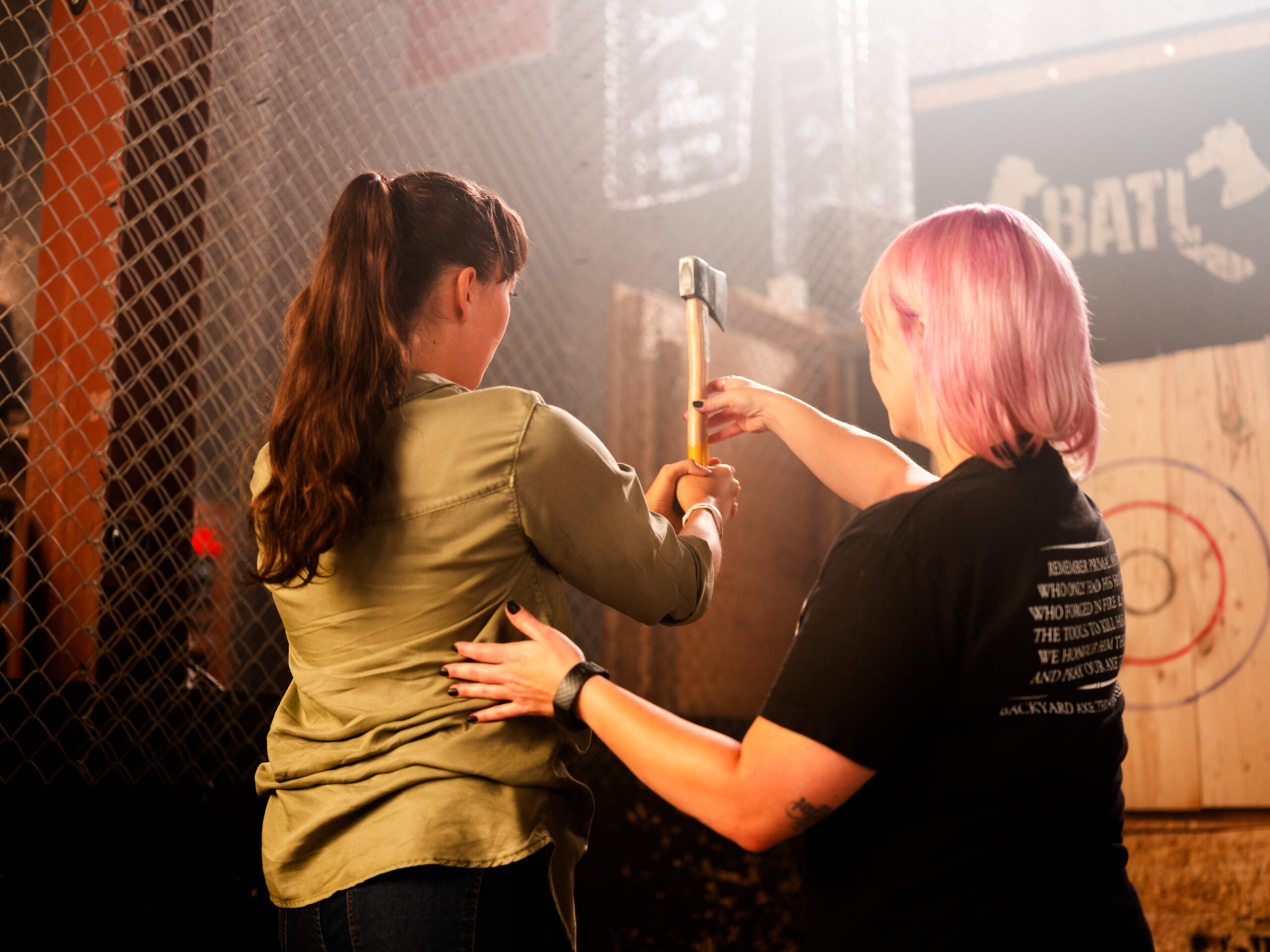 BATL-axe-throwing-coach-assisting-thrower.jpg A BATL Axe Throwing Coach helps a lady with her throw.